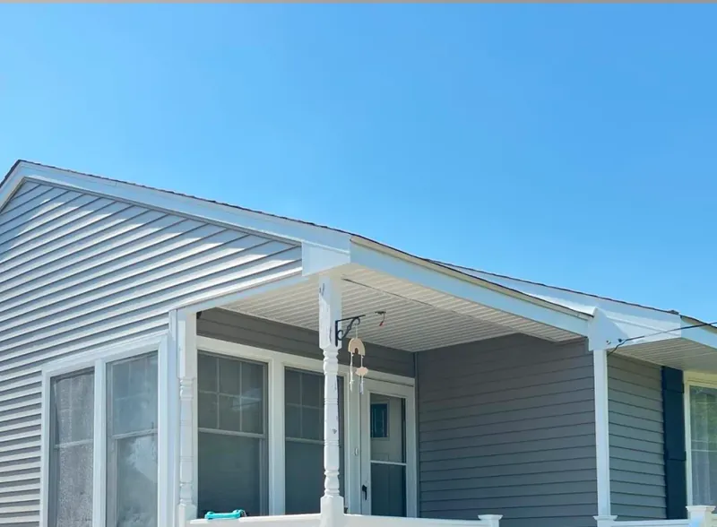 Covered front porch with white vinyl siding, white columns and a white soffit.
